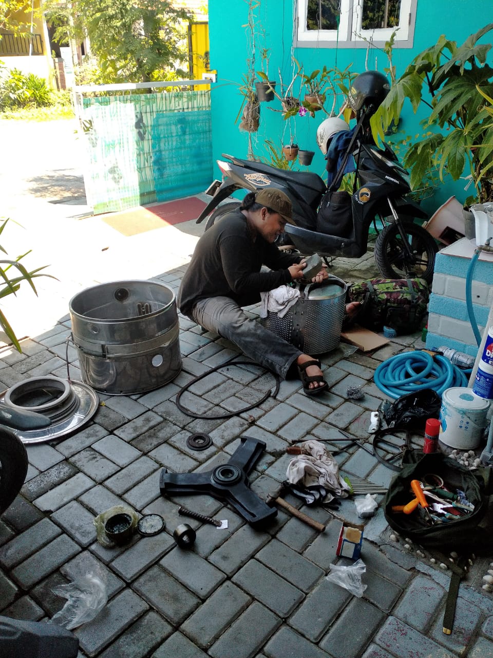 Close-up view of a technician's hands disassembling a washing machine drum with precision tools, showcasing professional repair work in a clean workshop environment