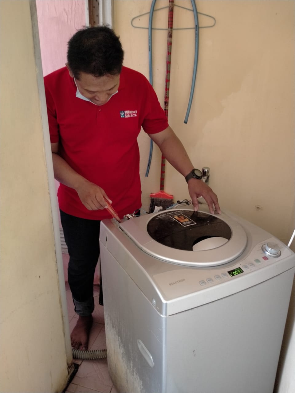 Close-up view of a technician's hands disassembling a washing machine drum with precision tools, showcasing professional repair work in a clean workshop environment