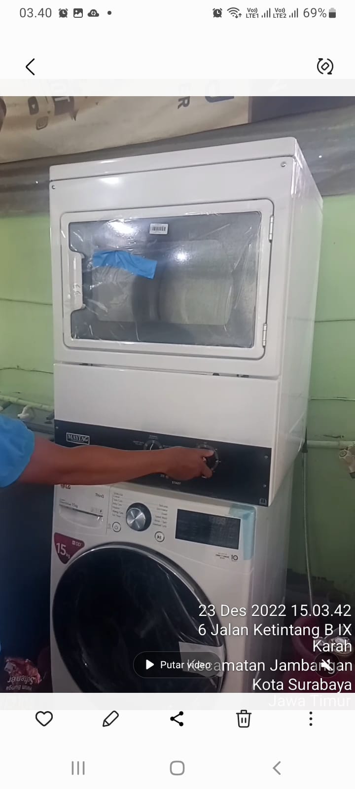 Team of technicians installing a new washing machine unit with hoses and electrical connections in a residential kitchen